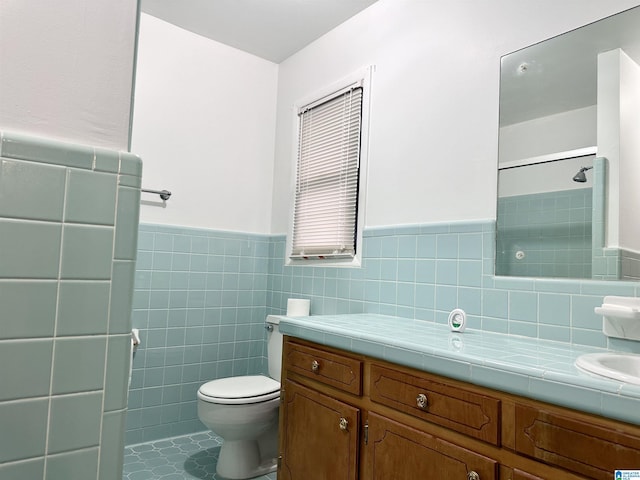 bathroom featuring toilet, tile walls, tile patterned floors, and vanity