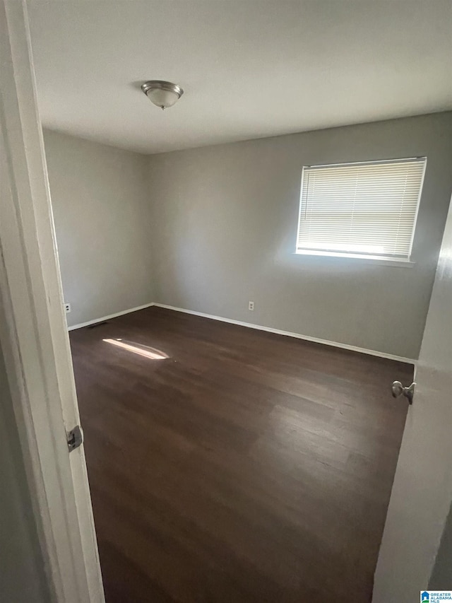 empty room with baseboards and dark wood finished floors