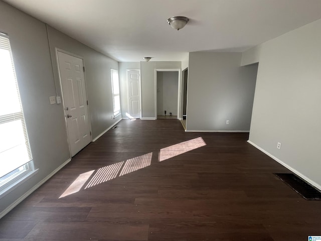 spare room featuring wood finished floors, visible vents, and baseboards