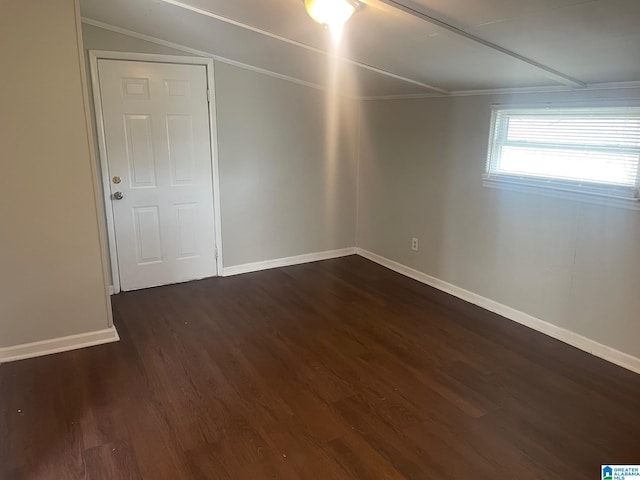 unfurnished room with baseboards and dark wood-type flooring