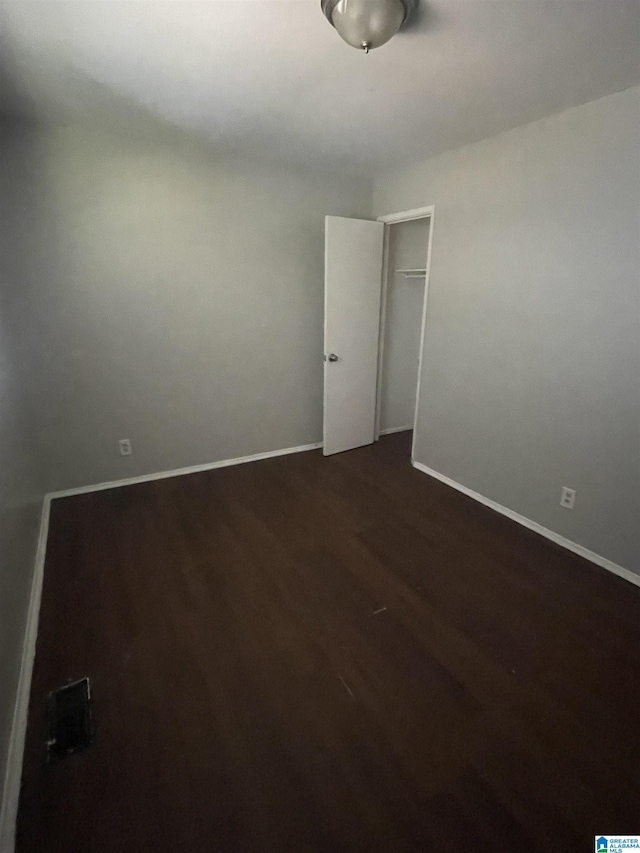 unfurnished room featuring dark wood-style flooring and baseboards