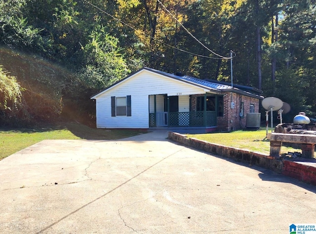 ranch-style home with a front lawn, a porch, and central air condition unit