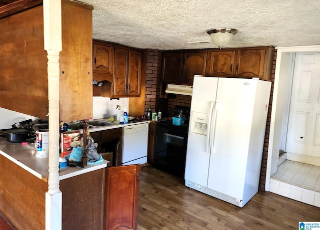 kitchen with dark wood-type flooring, white appliances, and a textured ceiling