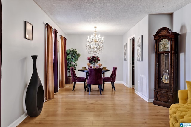 dining room featuring a chandelier, light hardwood / wood-style floors, and a textured ceiling