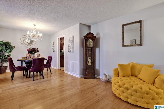 dining area with wood-type flooring, a textured ceiling, and a notable chandelier