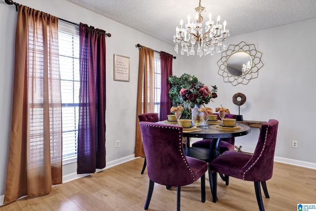 dining area with light wood-type flooring, an inviting chandelier, and a textured ceiling