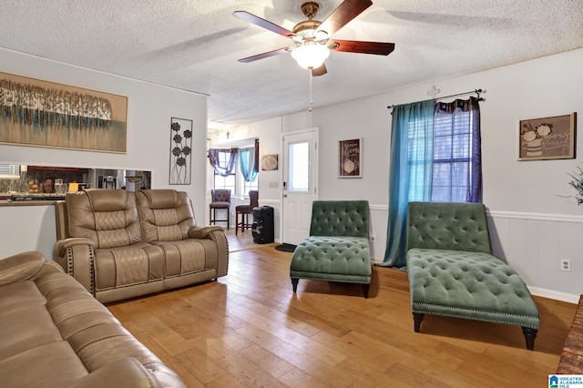 living room featuring ceiling fan, a textured ceiling, and wood-type flooring