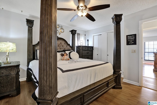 bedroom with ornate columns, a textured ceiling, hardwood / wood-style flooring, a closet, and ceiling fan