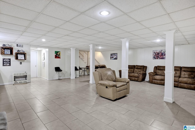 living room featuring decorative columns, a drop ceiling, and heating unit