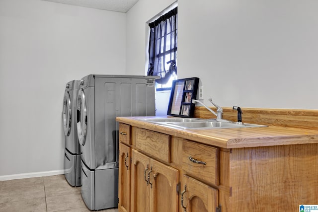 laundry area featuring sink, light tile patterned floors, separate washer and dryer, a textured ceiling, and cabinets