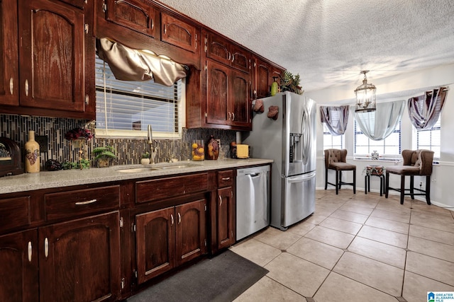 kitchen with hanging light fixtures, light tile patterned floors, sink, backsplash, and stainless steel appliances