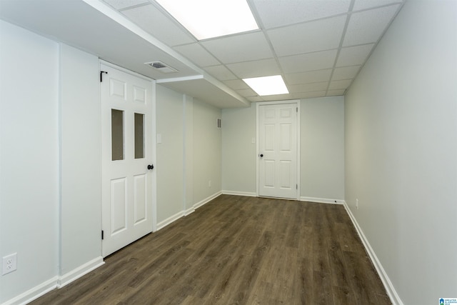 basement with a drop ceiling and dark hardwood / wood-style flooring