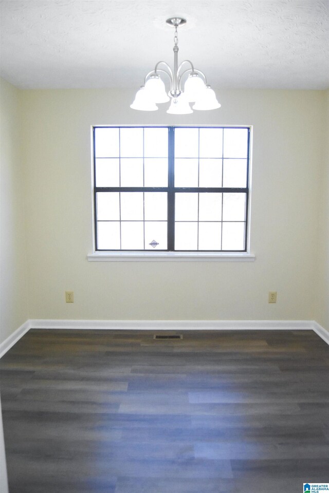 unfurnished dining area featuring a notable chandelier, plenty of natural light, and dark hardwood / wood-style flooring