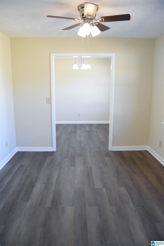 unfurnished room with ceiling fan with notable chandelier and dark wood-type flooring