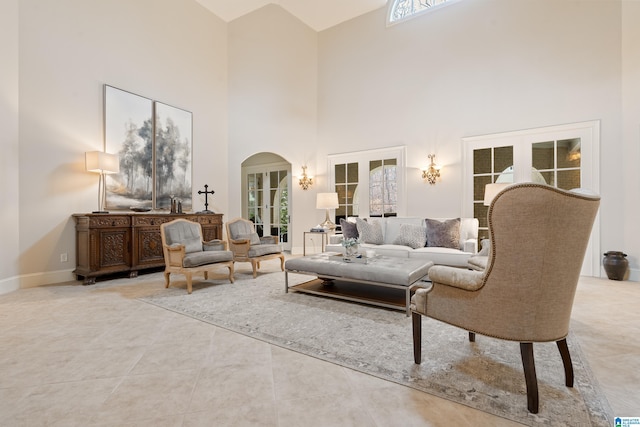 tiled living room with a towering ceiling and french doors