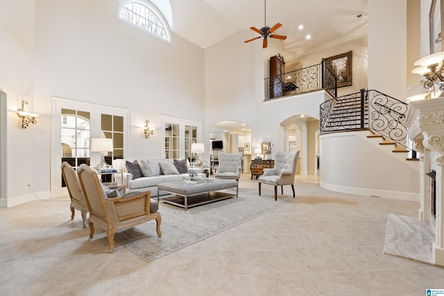 tiled living room with ceiling fan, a high ceiling, a wealth of natural light, and a high end fireplace