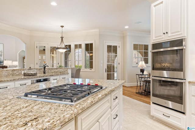 kitchen featuring light stone countertops, pendant lighting, crown molding, and stainless steel appliances