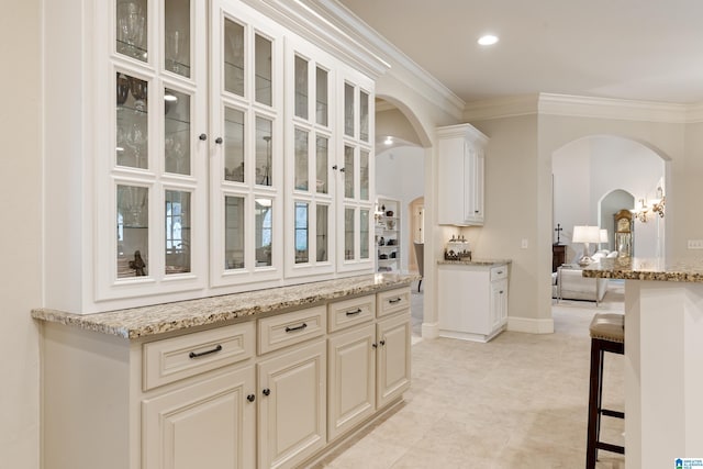 kitchen with ornamental molding, light stone countertops, and a kitchen breakfast bar