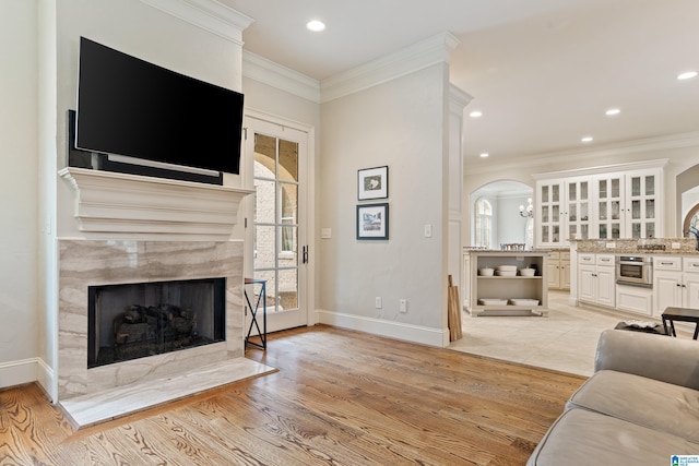 living room featuring light hardwood / wood-style flooring, a fireplace, and crown molding