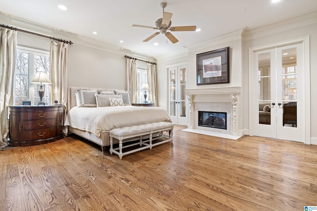 bedroom with ceiling fan, ornamental molding, french doors, and light wood-type flooring