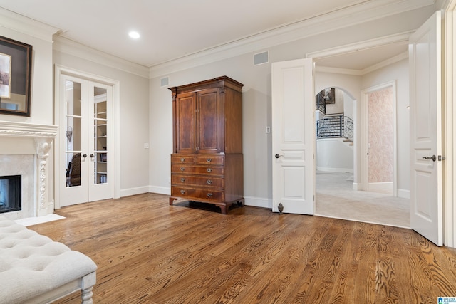 interior space featuring a premium fireplace, french doors, hardwood / wood-style floors, and crown molding