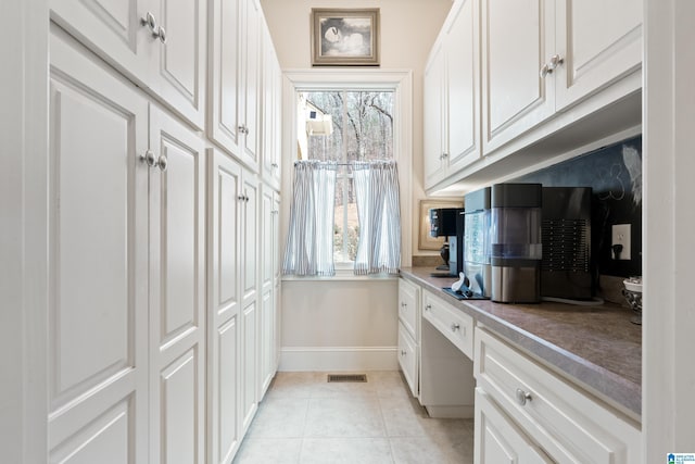 kitchen with light tile patterned floors, white cabinets, and built in desk