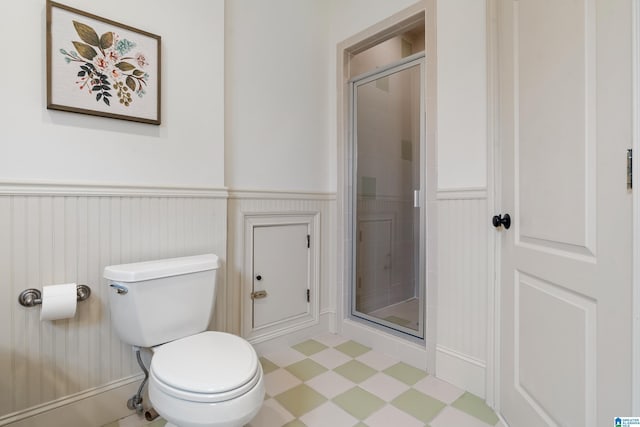 bathroom featuring toilet and a shower with door