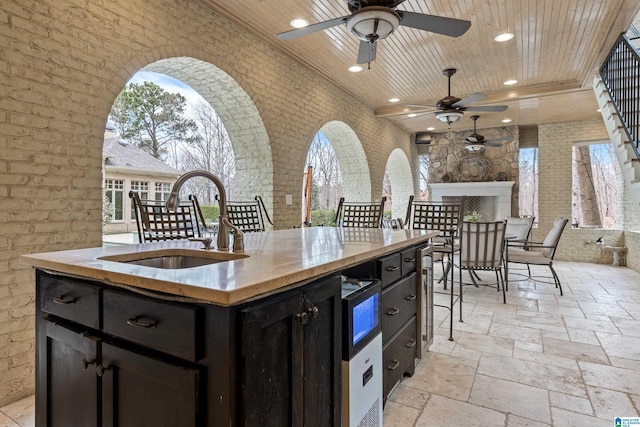 view of patio with ceiling fan, area for grilling, and an outdoor wet bar