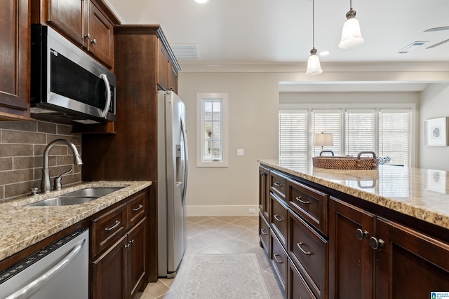 kitchen featuring appliances with stainless steel finishes, hanging light fixtures, sink, ornamental molding, and light stone counters