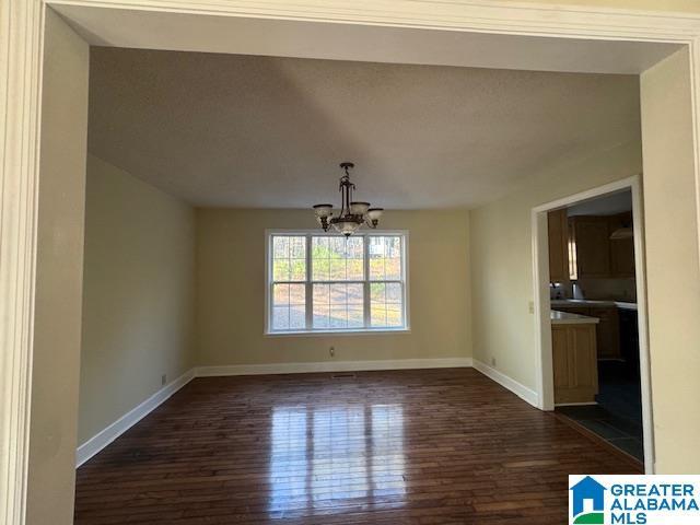 unfurnished dining area featuring an inviting chandelier and dark hardwood / wood-style floors