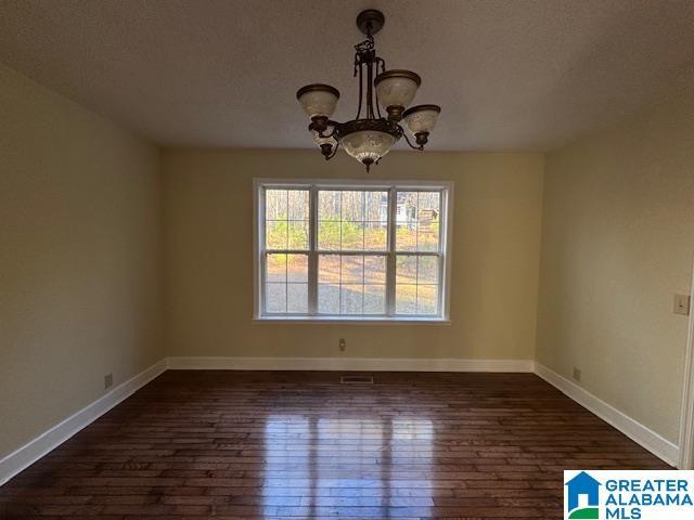 unfurnished dining area with an inviting chandelier and dark hardwood / wood-style flooring