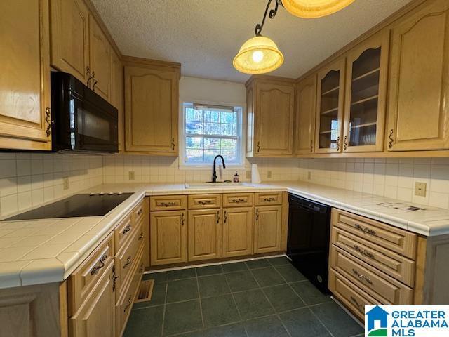 kitchen with black appliances, backsplash, hanging light fixtures, and sink