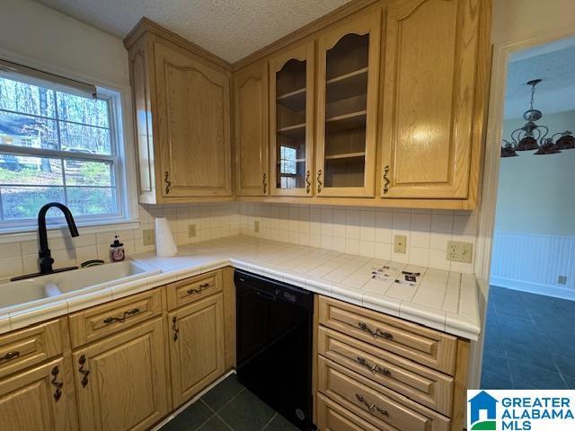 kitchen featuring black dishwasher, tile counters, decorative backsplash, dark tile patterned flooring, and sink