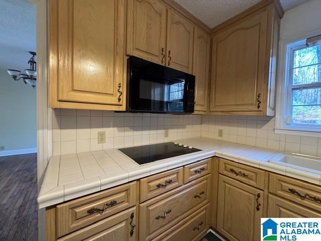 kitchen featuring decorative backsplash, sink, black appliances, and tile counters