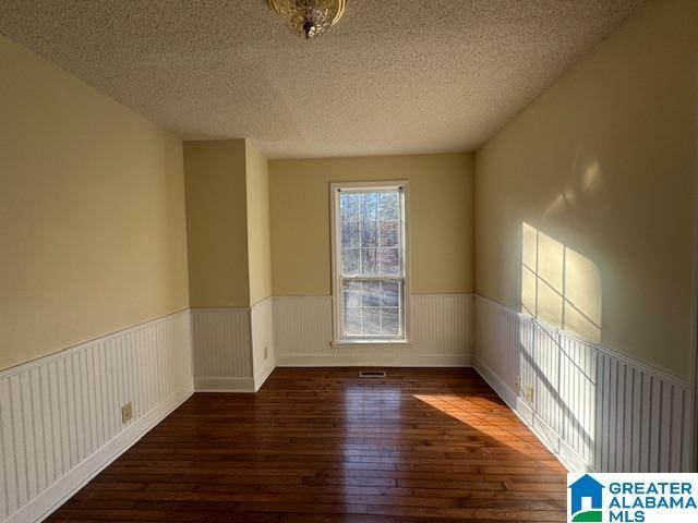 empty room with a textured ceiling and dark hardwood / wood-style floors