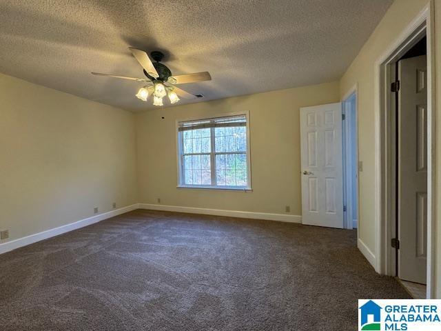 unfurnished bedroom with ceiling fan, dark colored carpet, and a textured ceiling