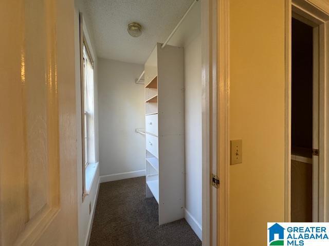 hall with a textured ceiling and dark carpet