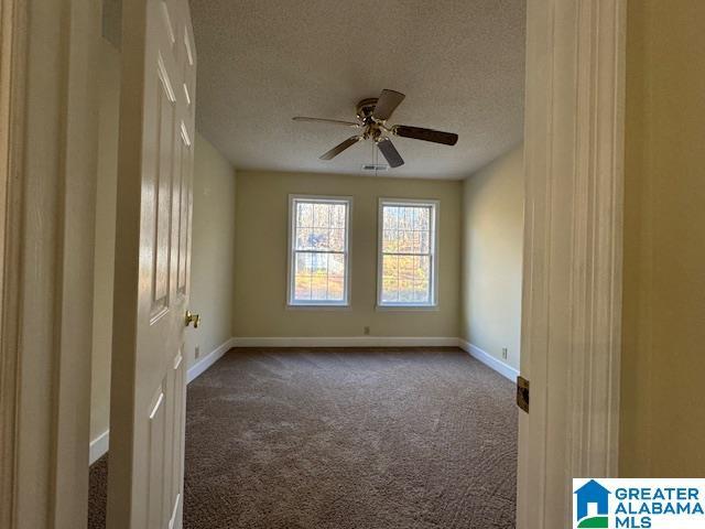 spare room with a textured ceiling, carpet flooring, and ceiling fan