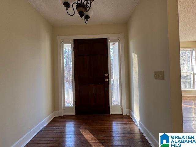 entrance foyer with an inviting chandelier, dark wood-type flooring, and a textured ceiling