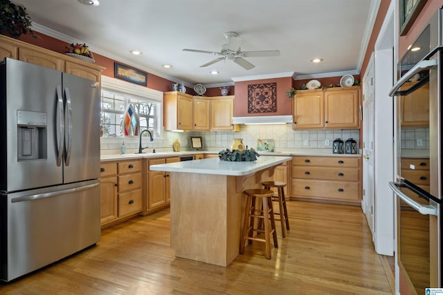 kitchen with a center island, stainless steel appliances, light hardwood / wood-style floors, a kitchen breakfast bar, and sink