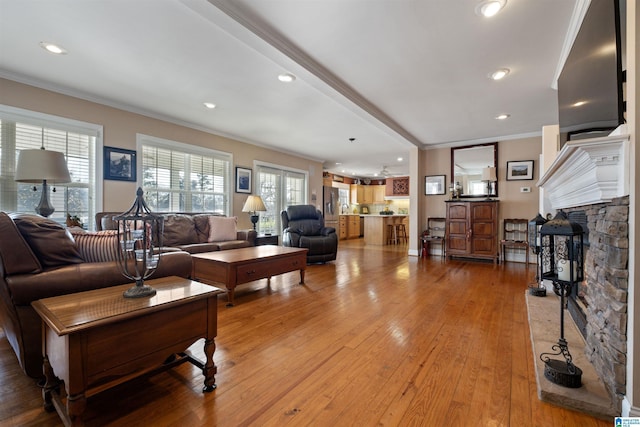 living room with hardwood / wood-style flooring, ornamental molding, and a fireplace