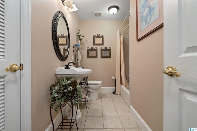 full bathroom featuring sink, shower / bath combo with shower curtain, toilet, and tile patterned floors