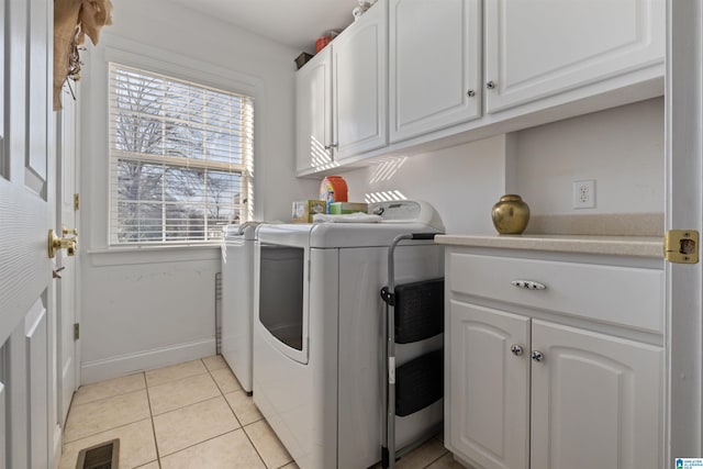 washroom featuring washer and clothes dryer, light tile patterned floors, and cabinets