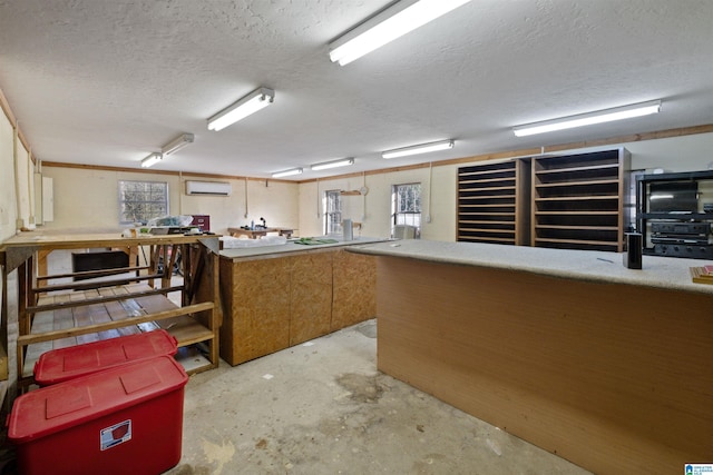 interior space with a wall mounted air conditioner, a textured ceiling, and a healthy amount of sunlight