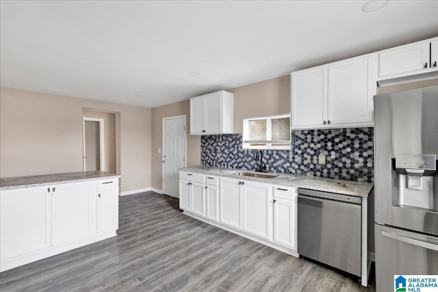 kitchen featuring appliances with stainless steel finishes, tasteful backsplash, sink, white cabinets, and hardwood / wood-style flooring