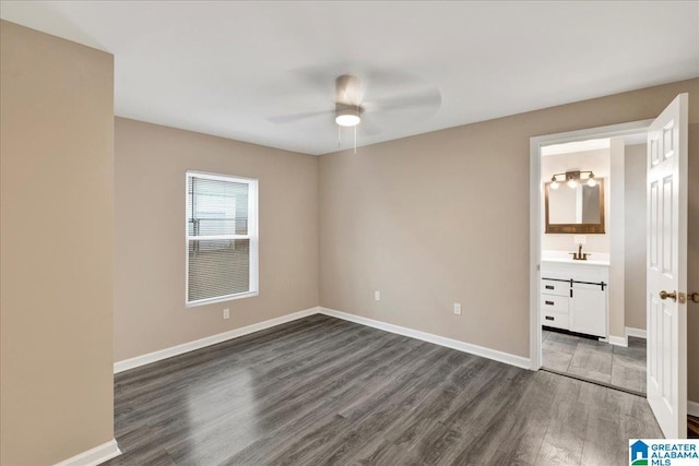 unfurnished bedroom with ensuite bathroom, dark hardwood / wood-style floors, sink, and ceiling fan