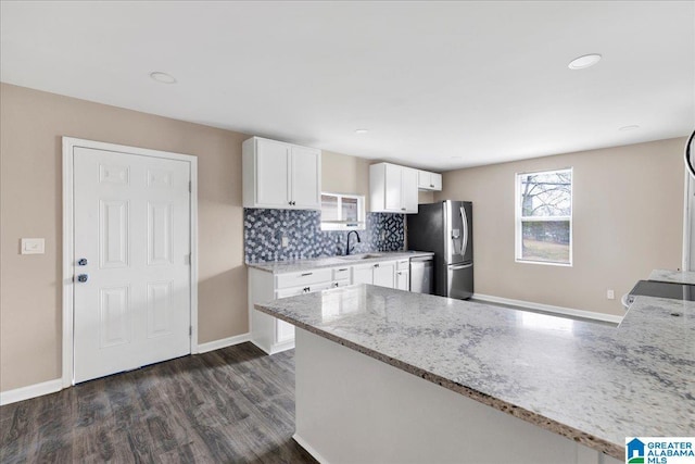 kitchen with sink, white cabinetry, dark hardwood / wood-style floors, stainless steel appliances, and light stone countertops