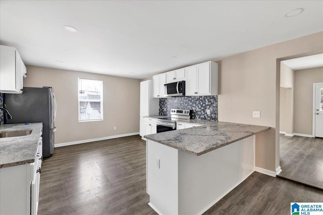 kitchen featuring white cabinetry, decorative backsplash, light stone counters, kitchen peninsula, and stainless steel appliances