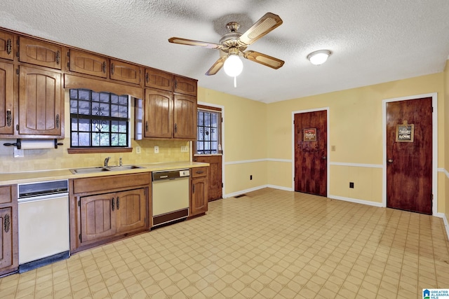 kitchen with sink, ceiling fan, backsplash, white dishwasher, and a textured ceiling