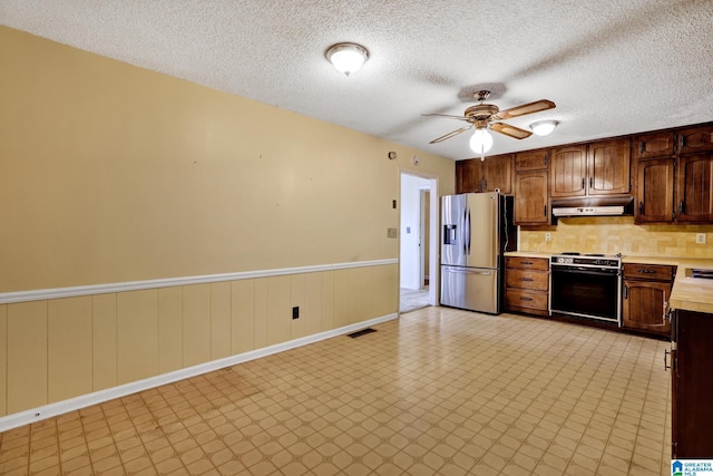 kitchen with tasteful backsplash, range, ceiling fan, stainless steel refrigerator with ice dispenser, and a textured ceiling